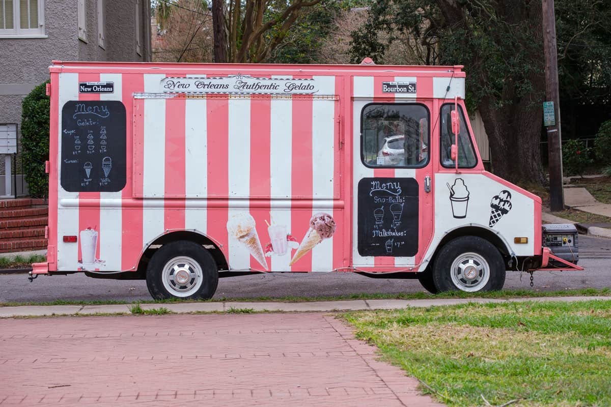 stripes white and pink colored ice cream truck on the park