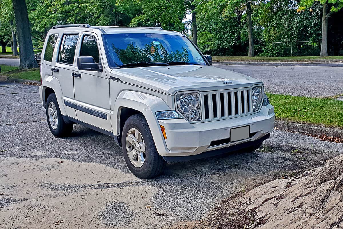  A 2010 Jeep Liberty parked in a wooded area, near a huge pile of sand