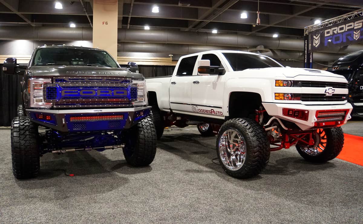 A Chevy and a Ford truck with a suspension lift kit