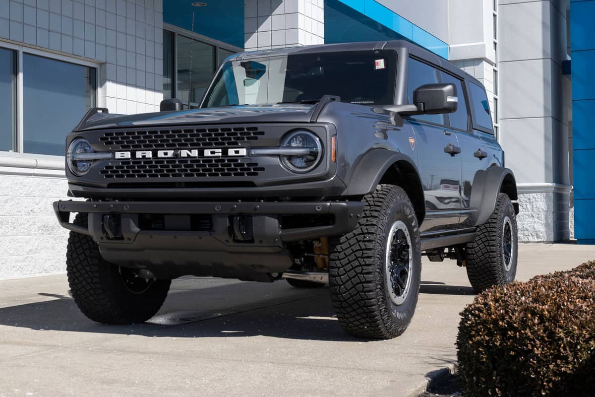A black Ford Bronco with huge lug tires parked next to a building