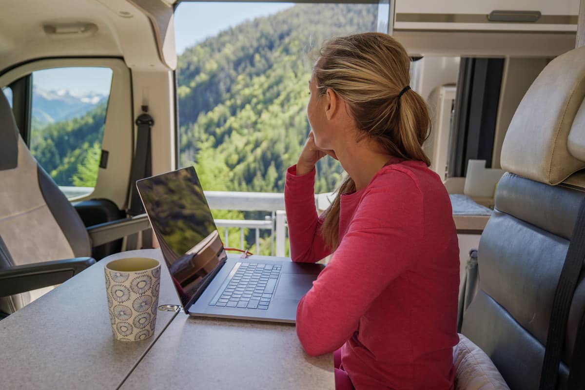 A freelancer working inside an RV with a scenic view of a mountain landscape