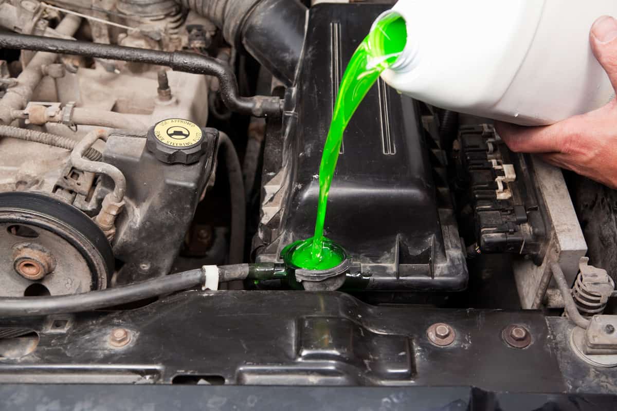 A mechanic is pouring antifreeze into a vehicle's radiator
