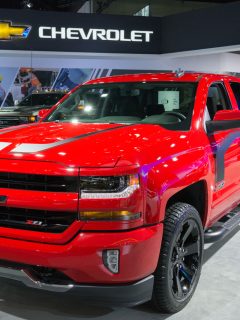 A red Chevrolet Silverado displayed at a car show, How Many Lugs On A Chevy Silverado? [Bolt Patterns Explained]