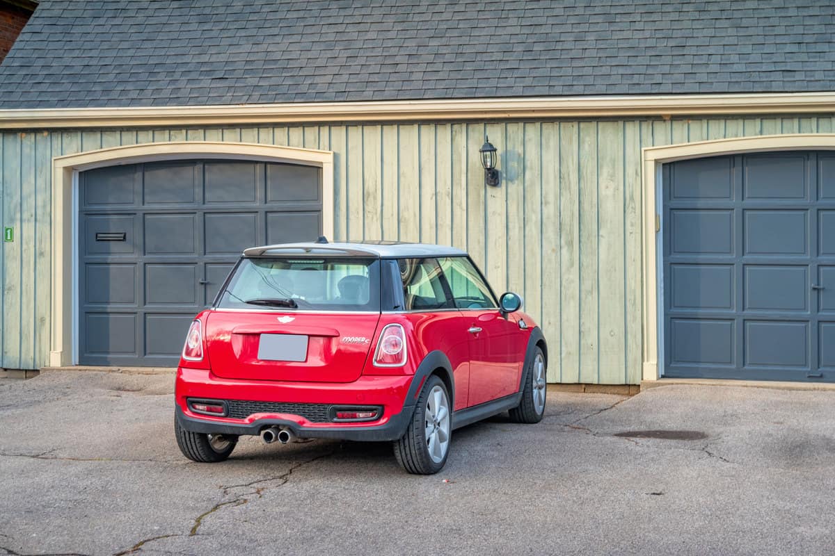 A red colored Mini Cooper parked near the garage
