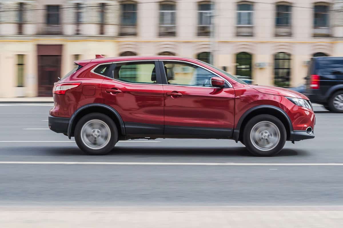 A red colored Nissan Rogue moving along the highway