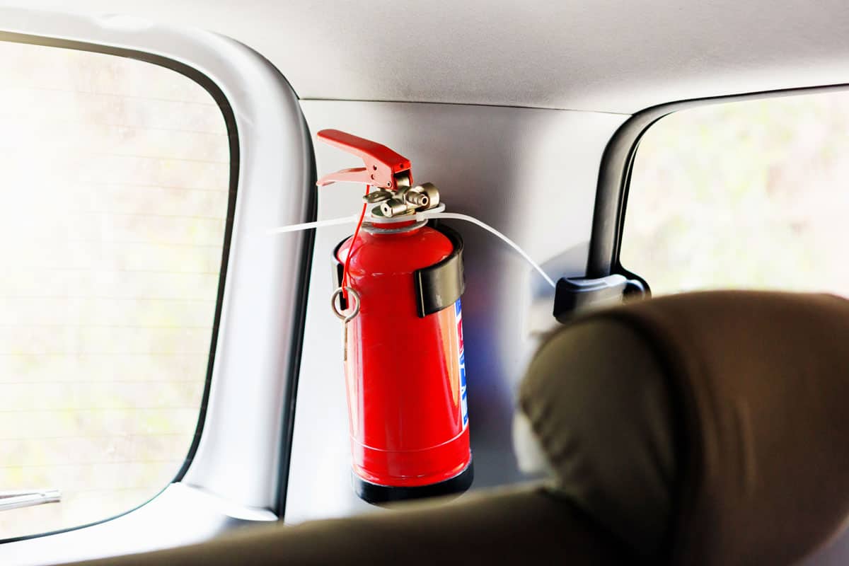 A small fire extinguisher is attached to a car's interior,
