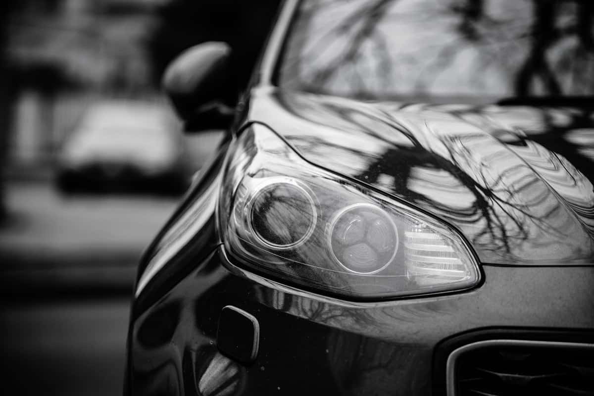 Black and white photo of a car showing its headlight