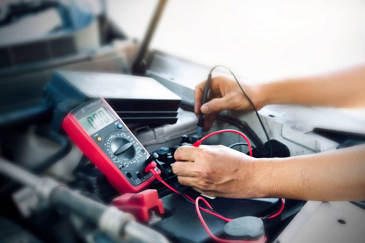 Car mechanic checking the battery using a voltmeter