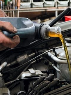 Car mechanic fills motor oil into a car engine - Will Adding Oil Make Car [And How To Tell If Your Oil Is Low]