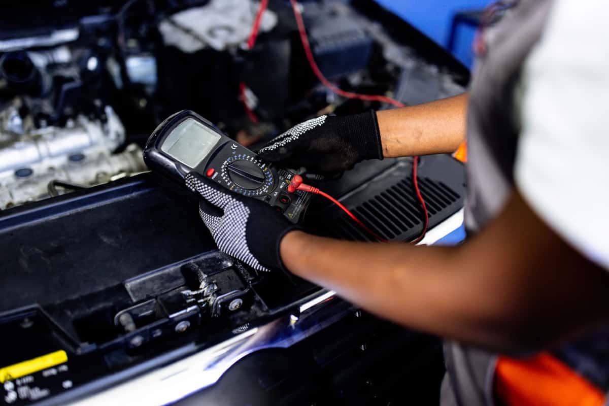 Car mechanic holding a diagnostic tool to check for engine errors