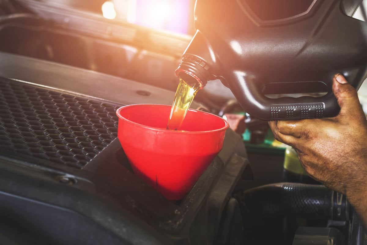 Car mechanic pouring new engine oil to the car engine