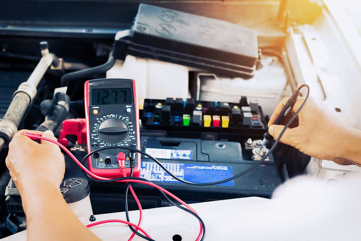 Car mechanic using a tester to checking the car battery