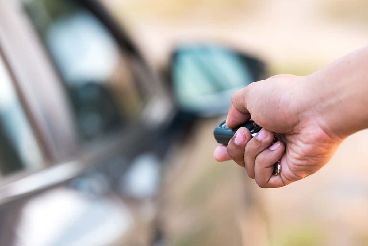 Closeup of a man's hand pushing unlock button on car remote