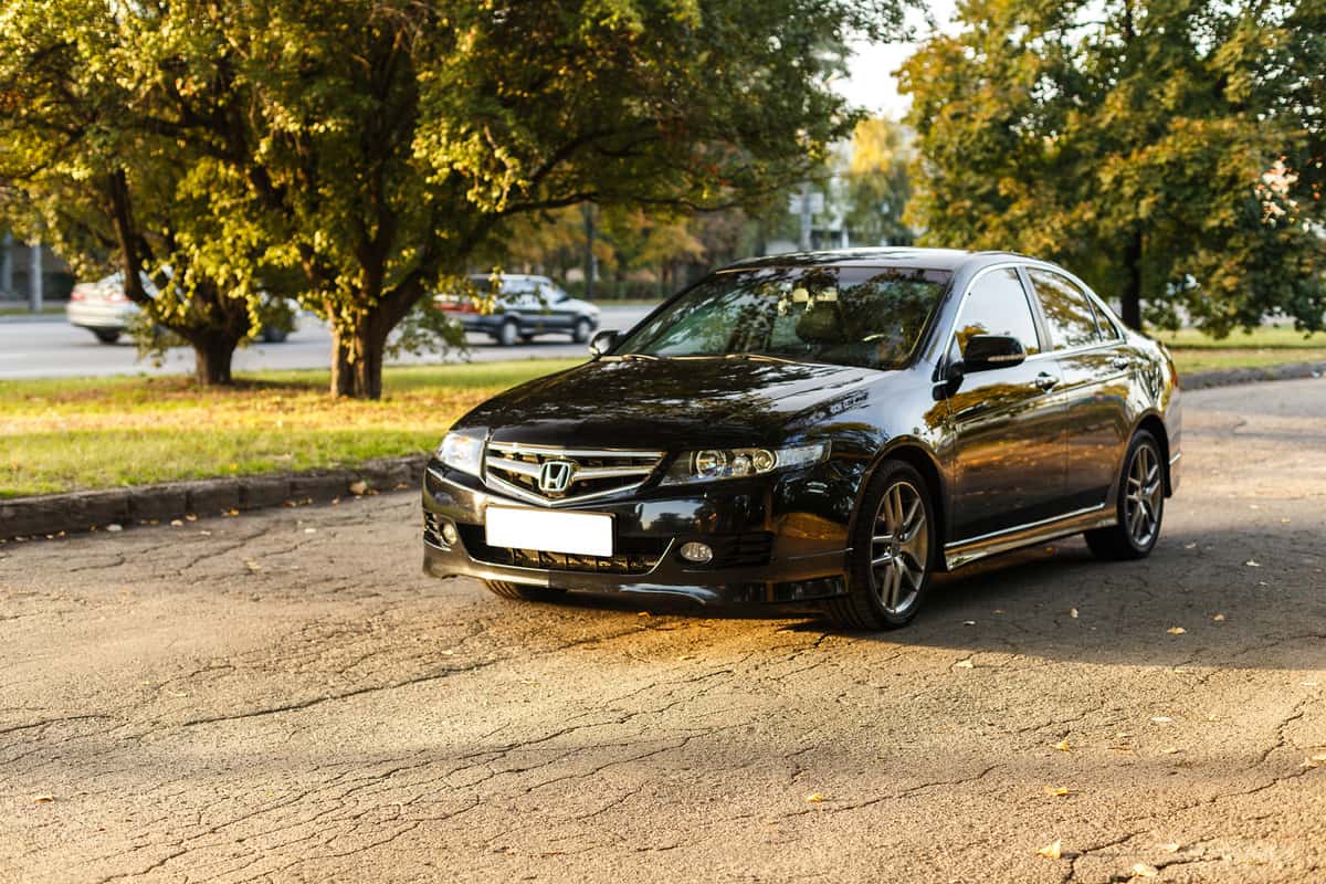 Honda Accord dark color on the walkway of Dnipro city street, autumn time. Cityscape on sunset.