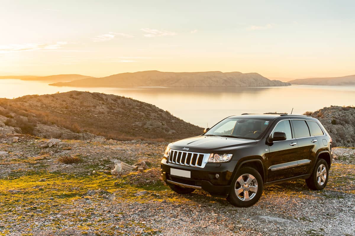 Jeep Grand Cherokee 3.0 TDI parked at the sunset on hill with beautiful seashore and islands of Adriatic sea in the background.