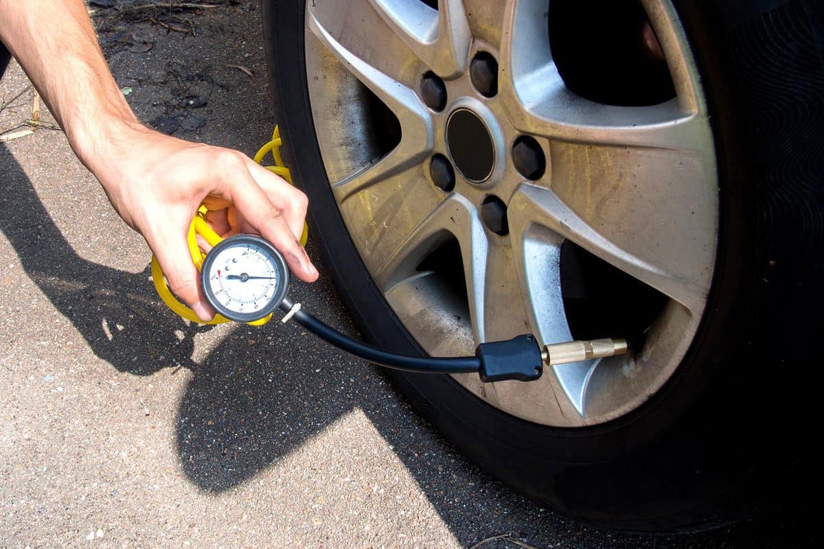 Male hand inflates and checks the pressure in the tires of a car