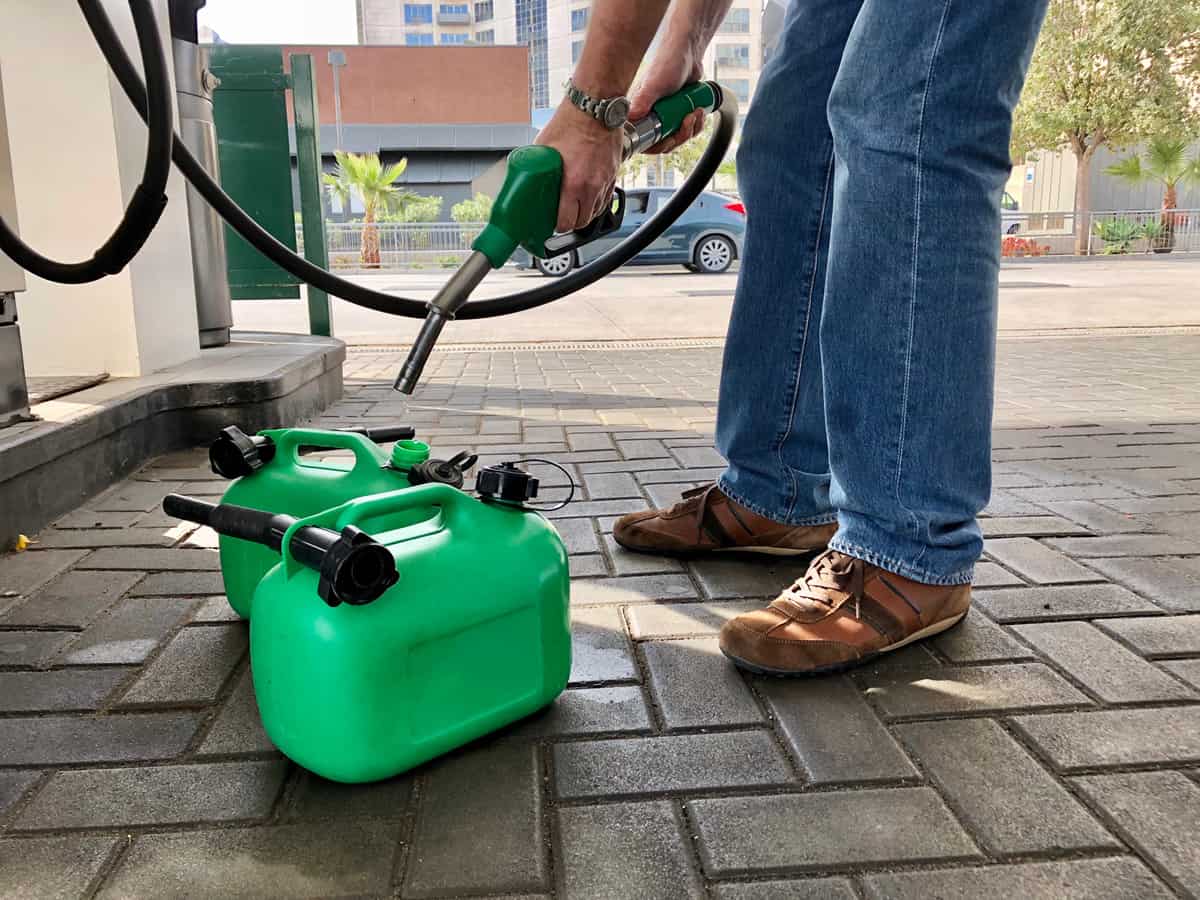 Man filling plastic fuel cans at a petrol station