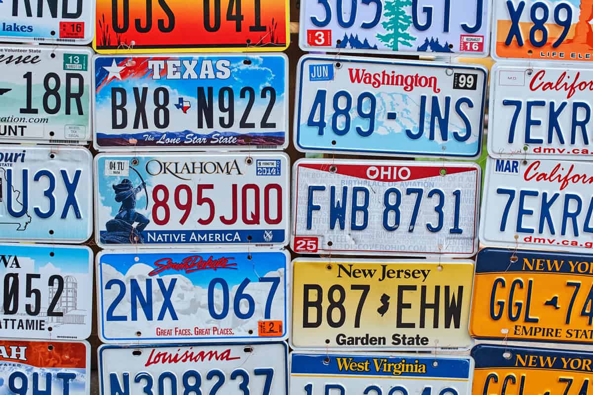 Old discontinued car license plates or vehicle registration numbers from different USA states on sale.