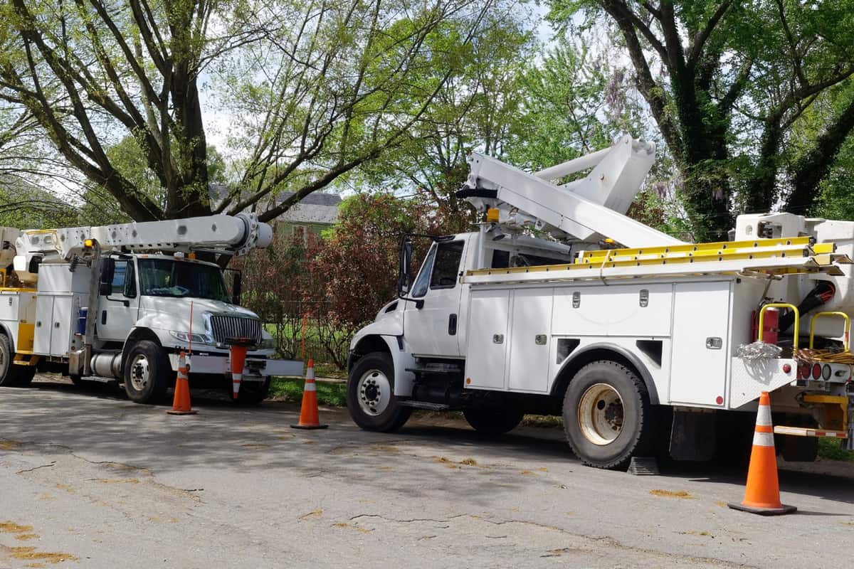 Parked telecommunications utility vehicle on shaded neighborhood street.