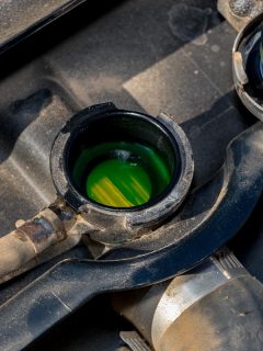 A radiator with cap removed showing green antifreeze coolant level inside, Where Does Antifreeze/Coolant Go In Your Car?