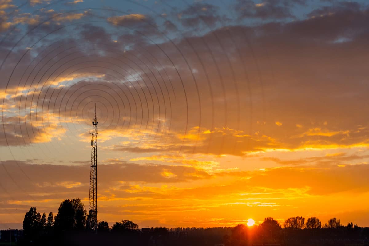 Radio waves escaping from gsm tower visualisation at sunset in rural area