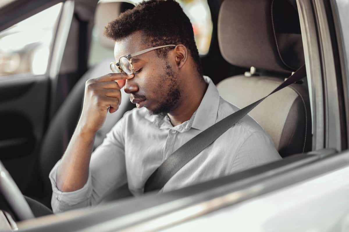 Stressed businessman feeling headache in car, stop the car, keeping hand to head and feeling anxiety