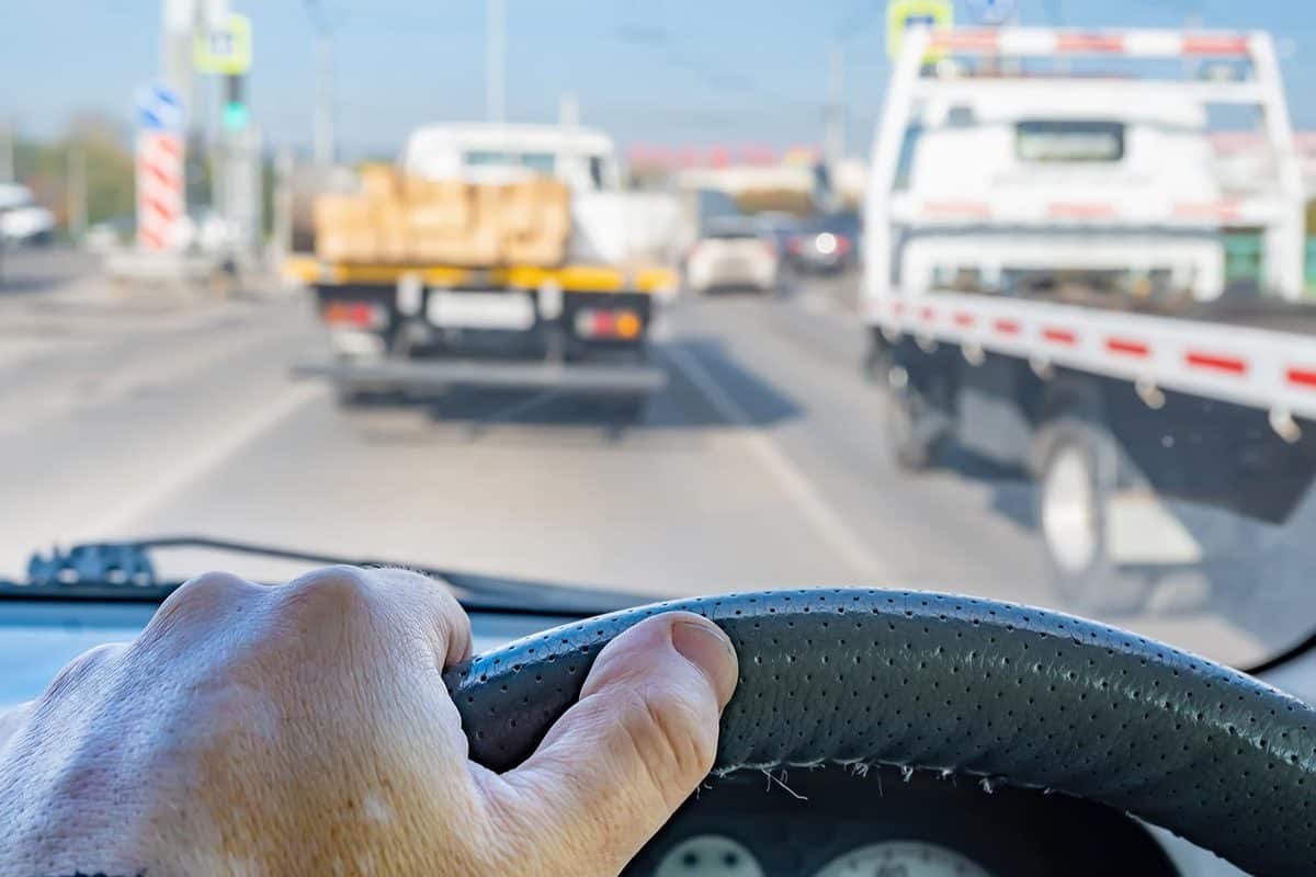 The driver's hand on the steering wheel inside the car during a traffic jam
