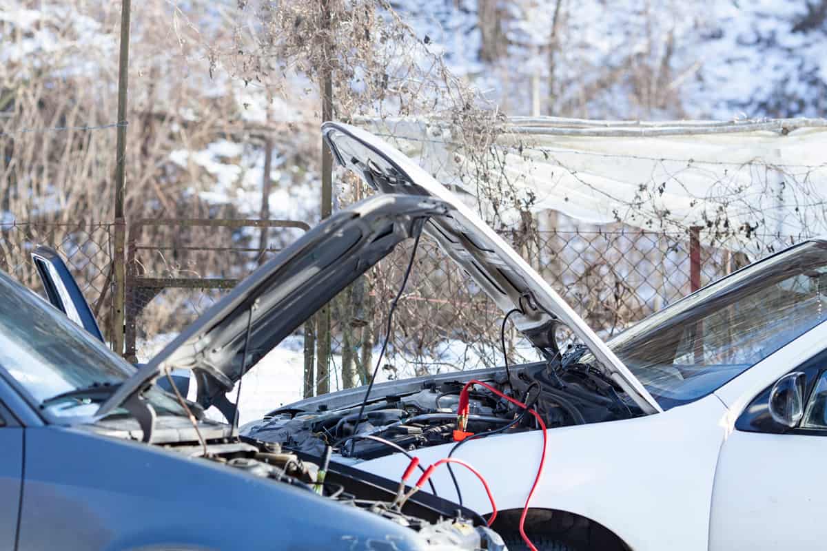 Two Parked Cars Sharing Battery Charge via Jumper Cables in Cold Weather.