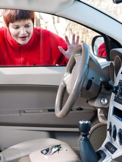 A woman looking into a car after locking her keys inside, How To Get Keys Out Of Locked Car With Automatic Locks [4 Solutions To Try]