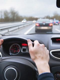 driving car on highway, close up of hands on steering wheel - How Long Can You Drive A Car Continuously