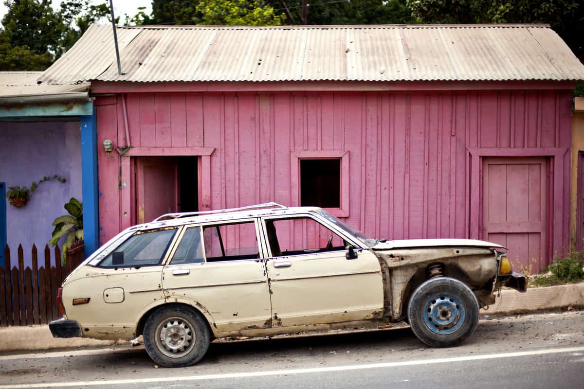 old car in front of pink building