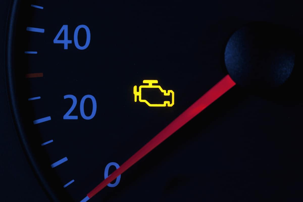 yellow engine check engine icon on car dashboard, black background