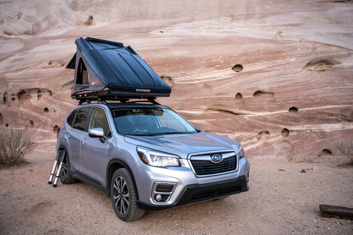 A gray colored Subaru Forester with a tent set up outside