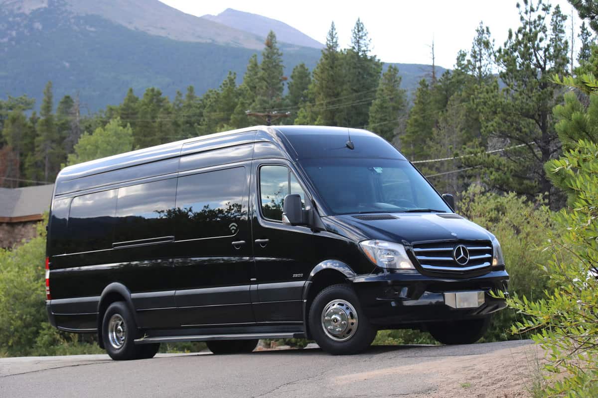 A long black Sprinter van on the side of the road