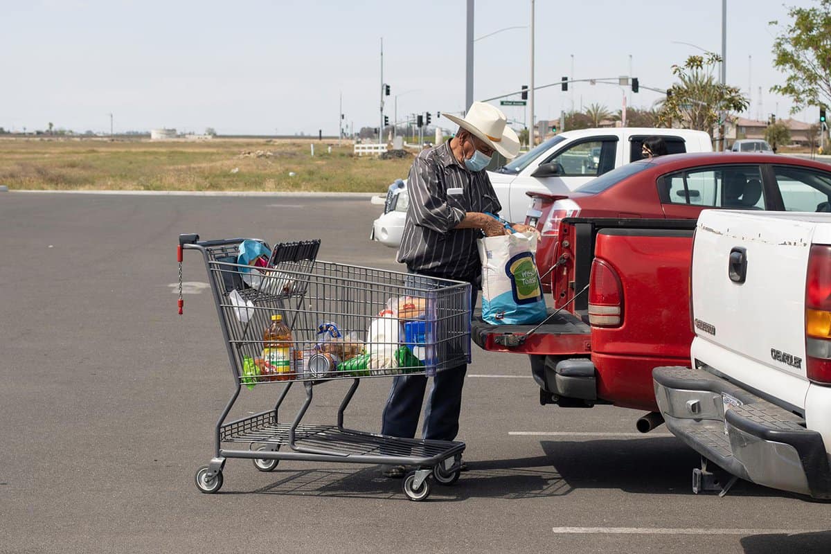 A masked customer bags his purchases after shopping at an Aldi grocery store in Delano