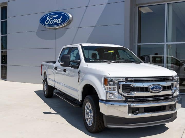 A white Ford F-250 parked outside a Ford dealership, What Does My Ford VIN Mean? Build Sheet Explained