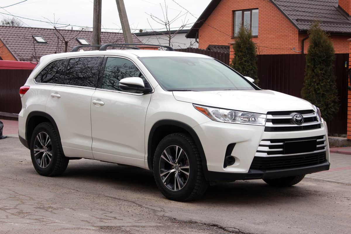 A white Toyota Highlander parked outside a house