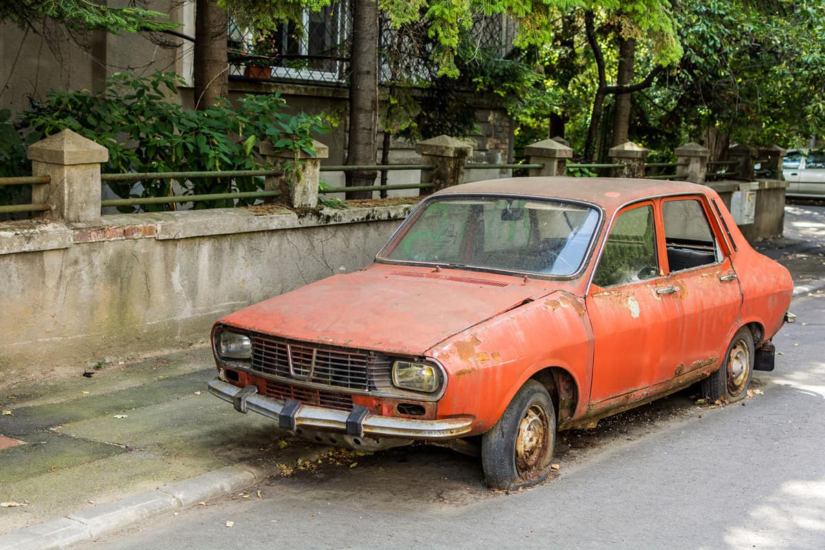 Abandoned red vintage Romanian Dacia 1300 with flat tires