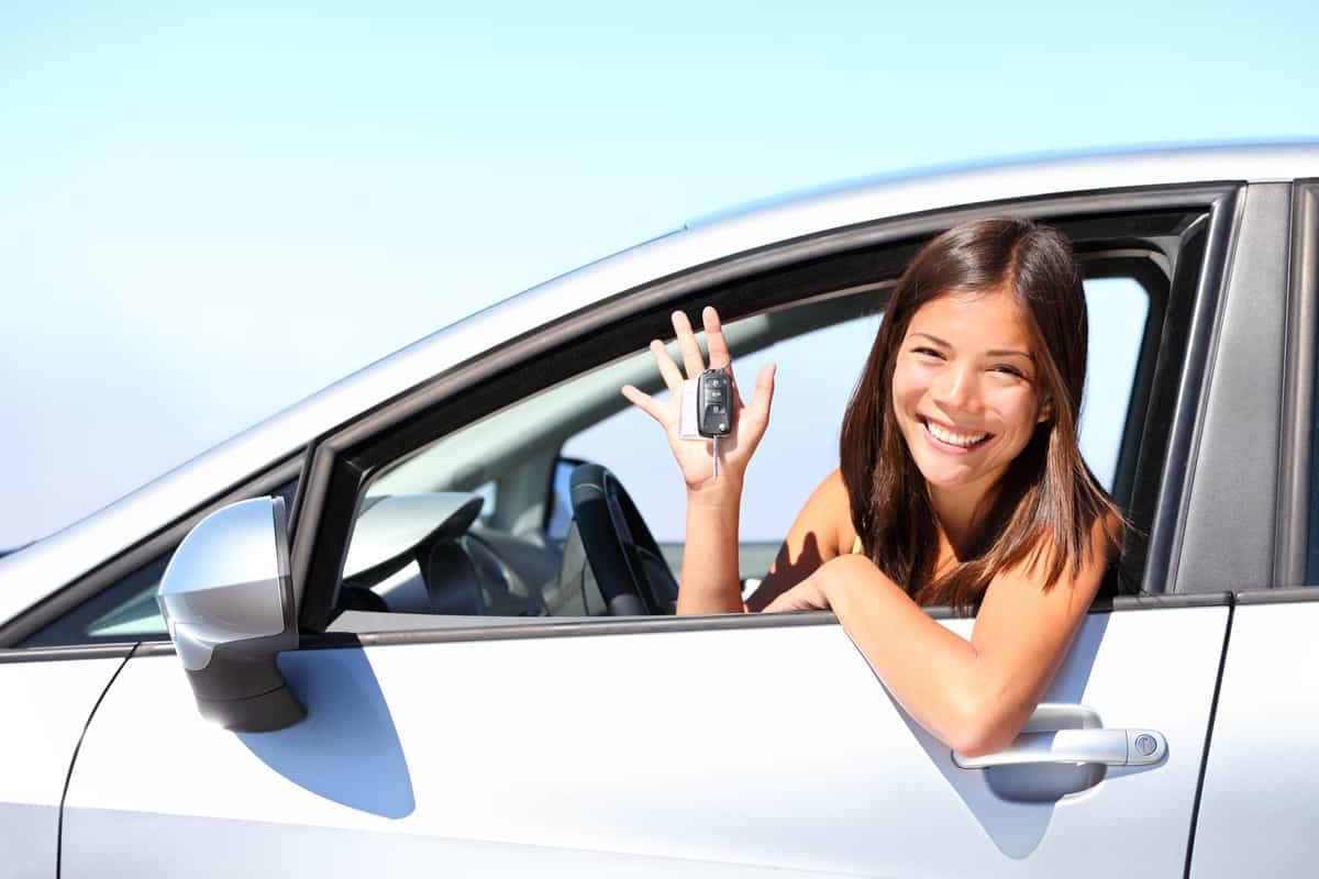 Asian car driver woman smiling showing new car keys and car.