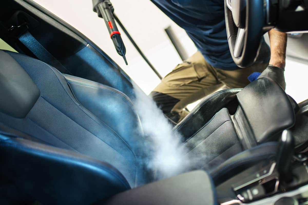 Auto detailing technician fogging the interior of the car
