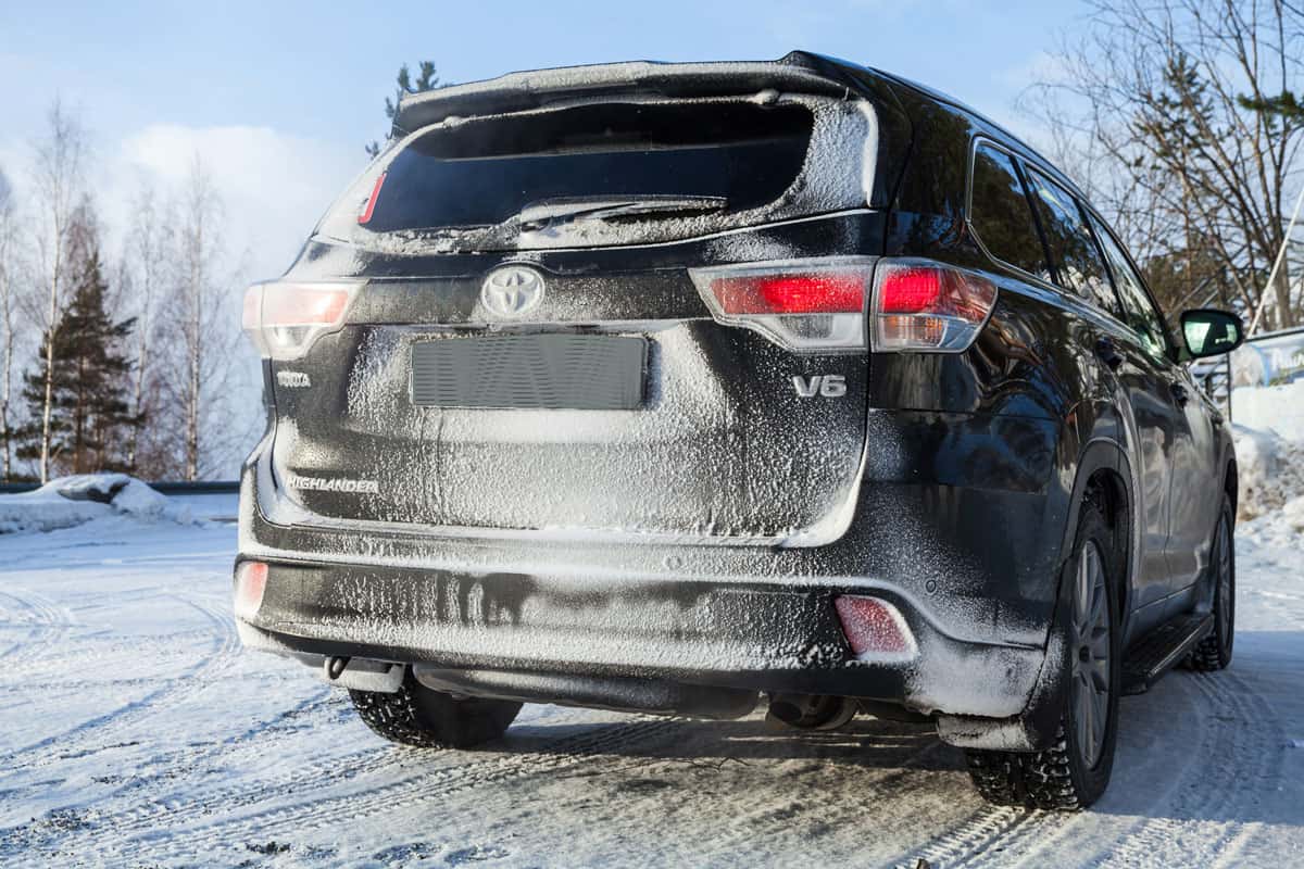 Black Toyota Highlander car stands on a roadside in winter season