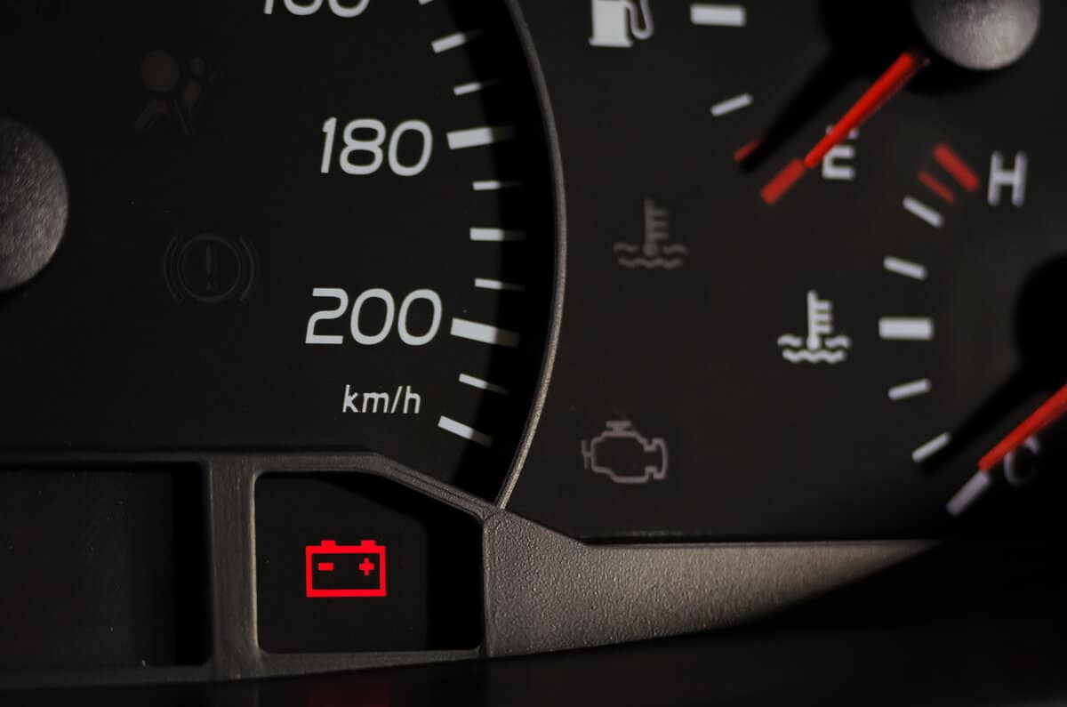 Close up shot of a car's dashboard with the battery icon lit.
