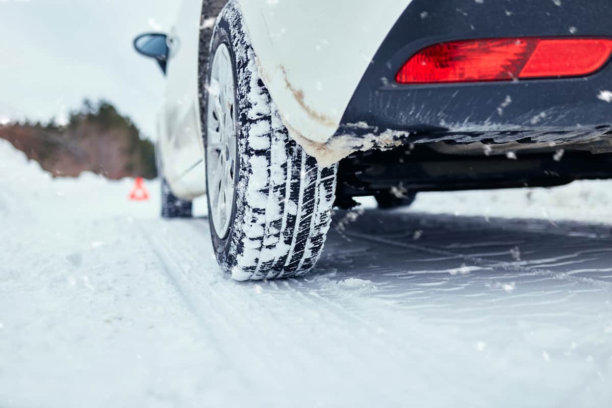 Close up shot of winter car tire on snowy road. Winter transportation concept.