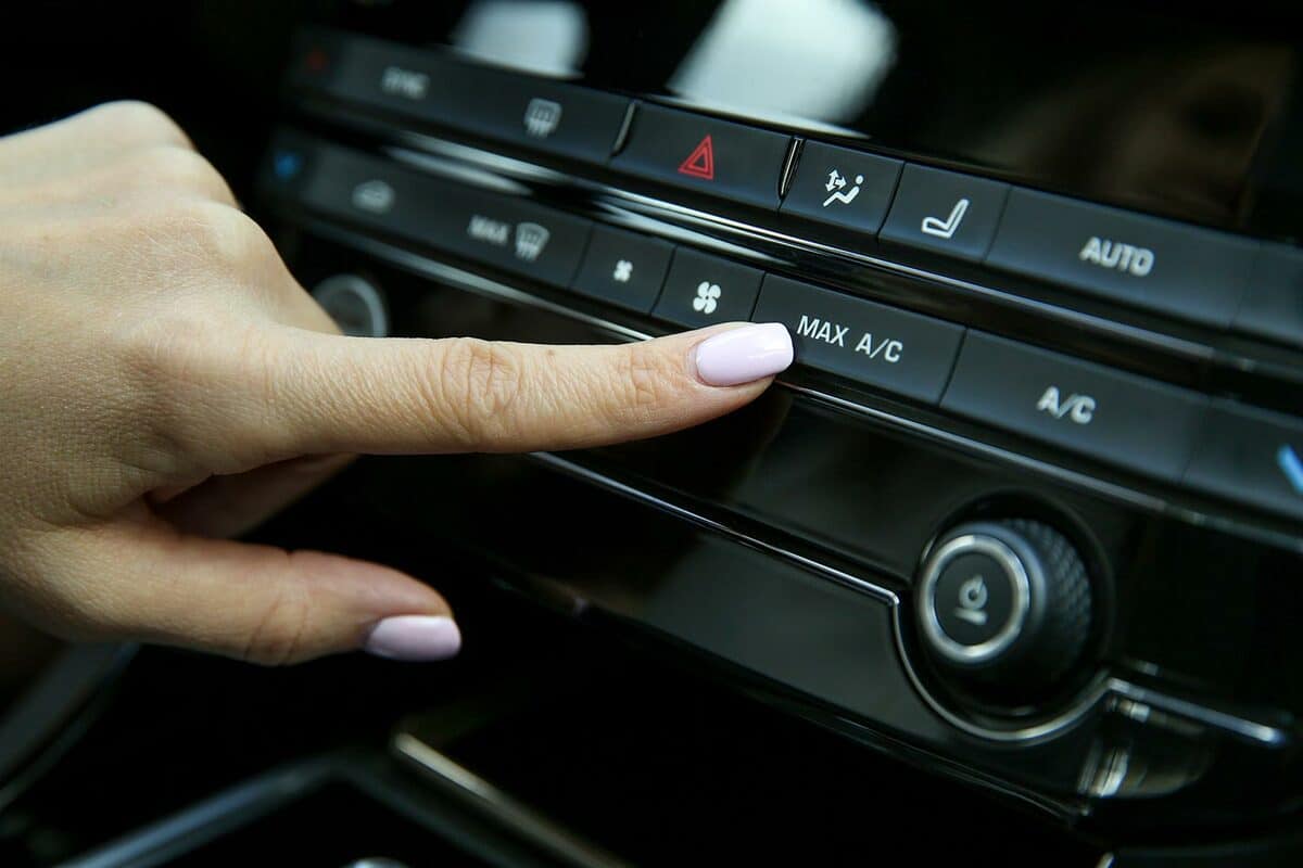 Driver's finger presses the button for maximum air conditioning inside the car