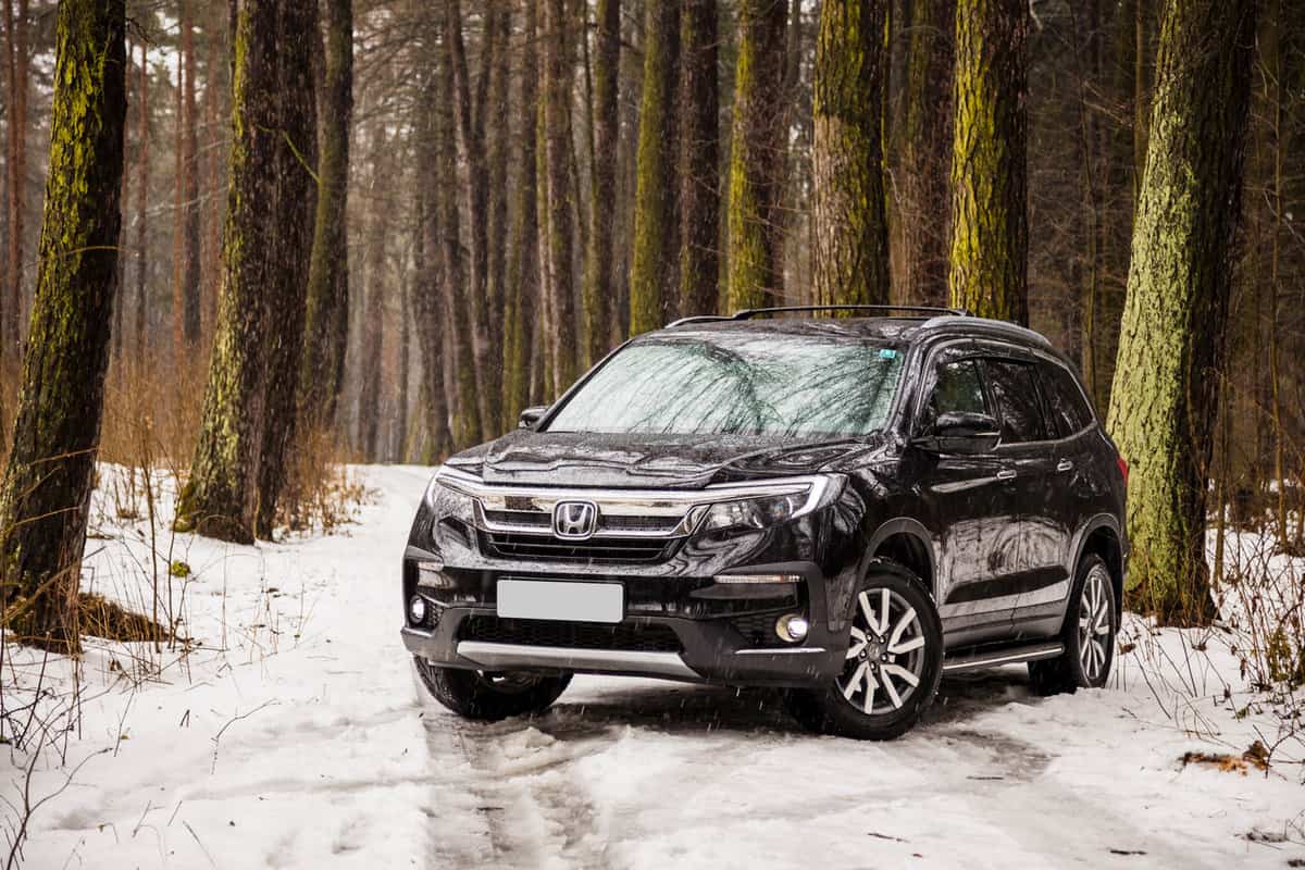 Exterior of the new premium SUV Honda Pilot in winter forest landscape