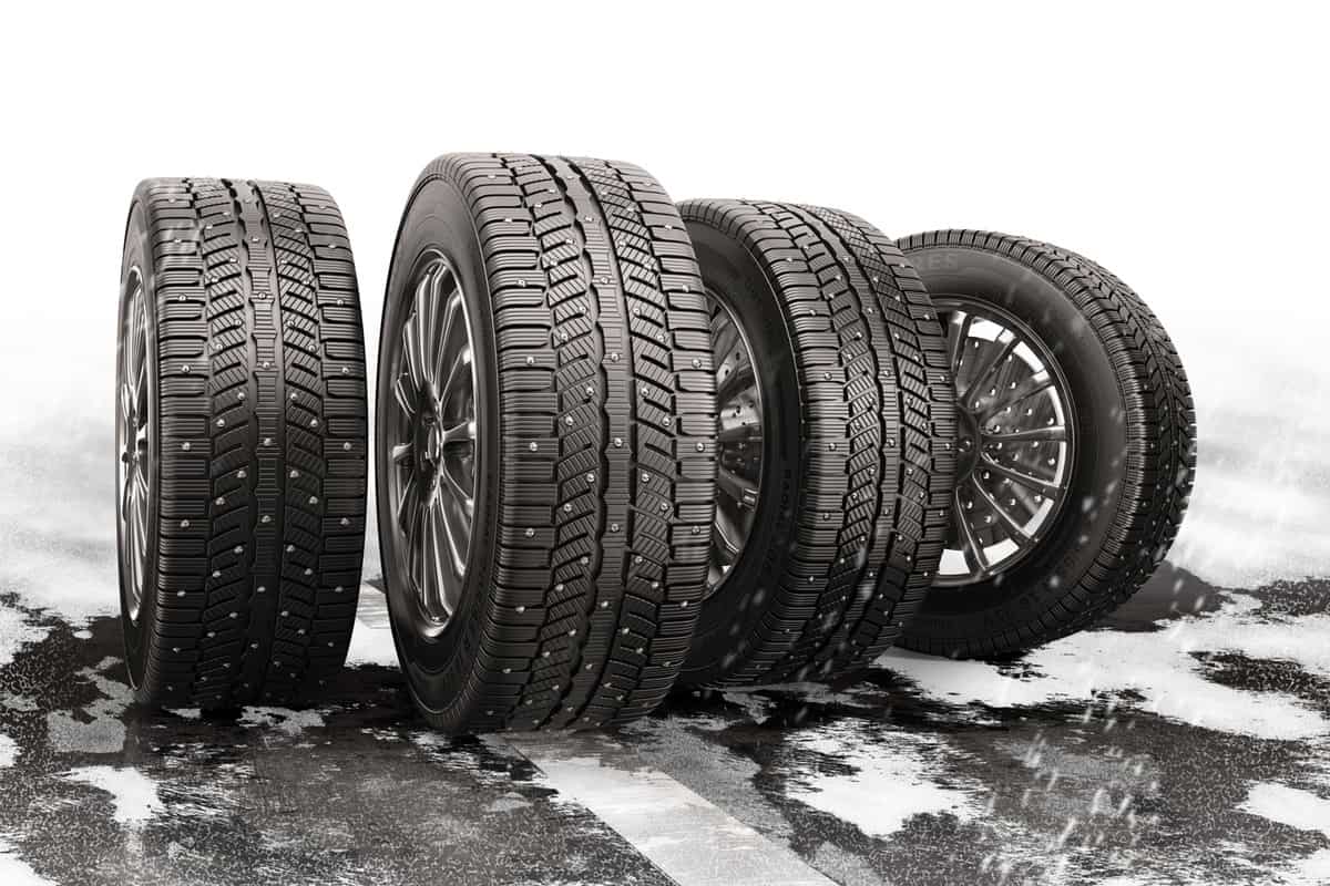 Four car tires rolling on a snow-covered road. 