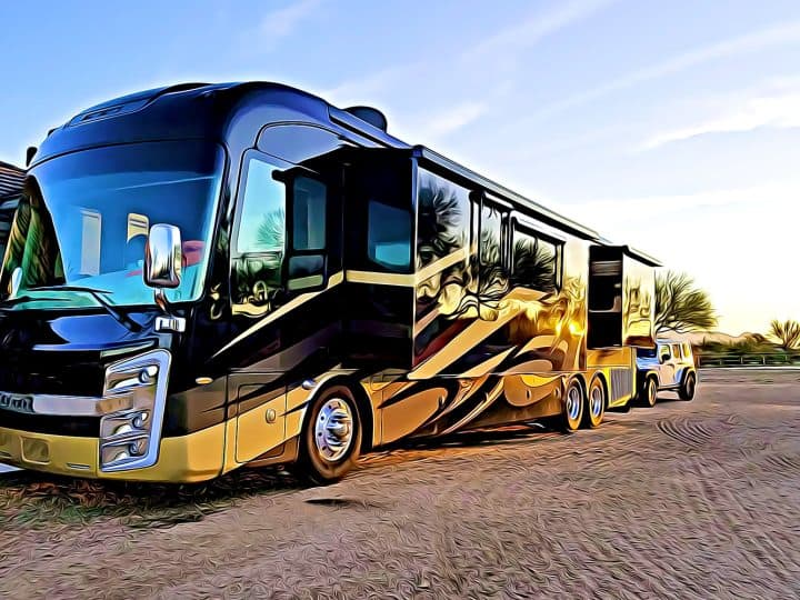 Luxury Motorhome recreational vehicle RV parked on dirt lot at sunset with reflections of trees