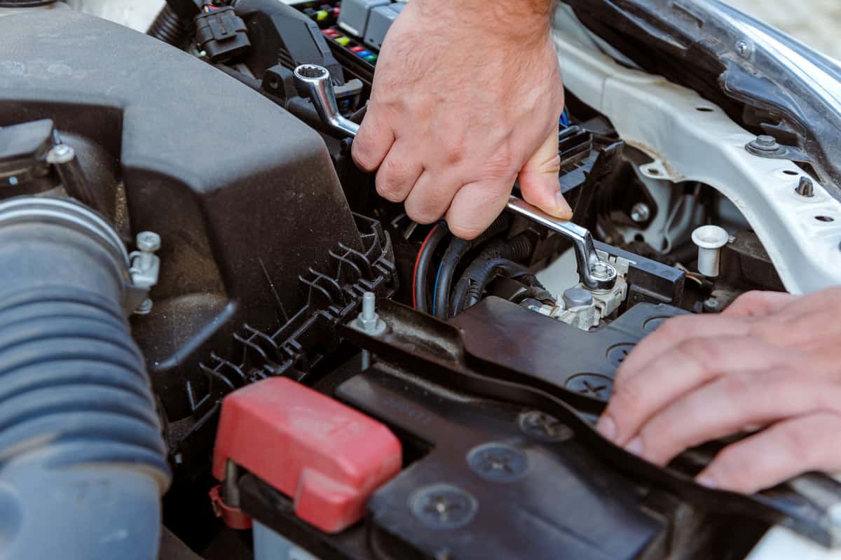 Man removing the car battery nut to replace it