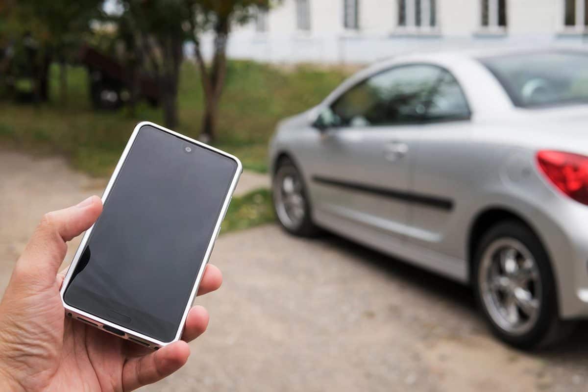 Man using smart phone to check status and control his new car