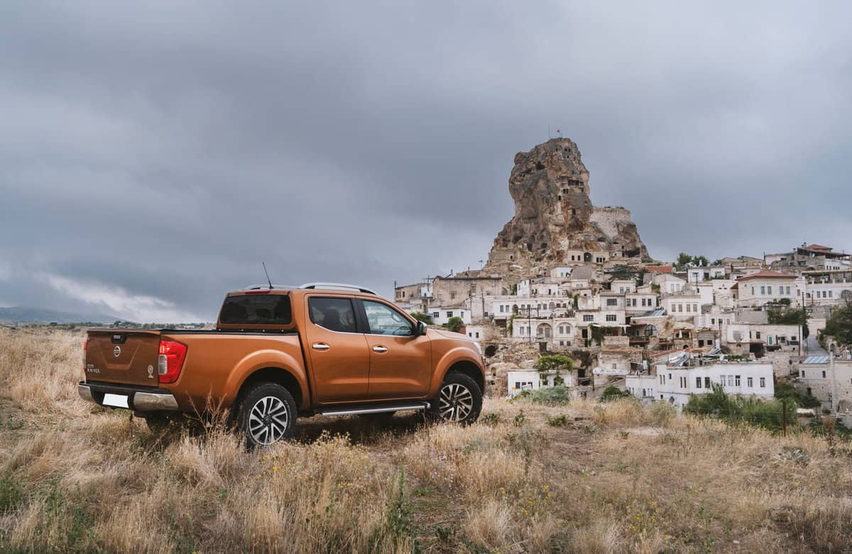 Nissan NP300 Navara stopped on the hill near Ortahisar Castle in Cappadocia. The newest generation of Navara was debut in 2015 on the market. The Navara is powered by 2,3-litre diesel engine and 190 HP. Ortahisar natural rock castle and town on the background.